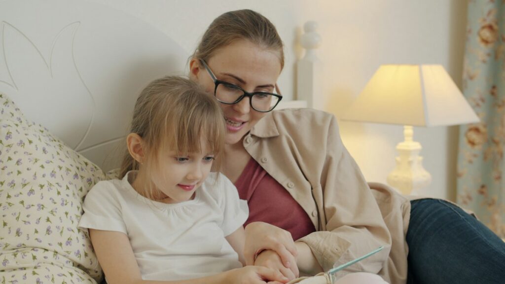 Mère et enfant lisant une histoire au lit à la lumière d’une lampe douce